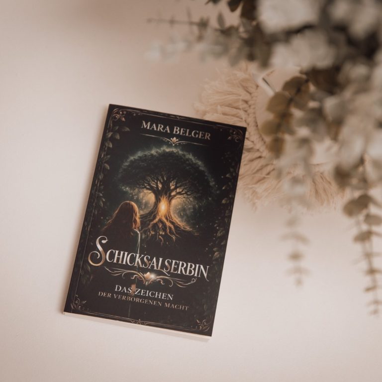 Schicksalserbin - Das Zeichen der verborgenen Macht Ein Buch mit dem Titel „Schicksalserbin“ steht auf einem Tisch, umgeben von Pflanzen und Arbeitsmaterial.
JonahLu-Fotografie